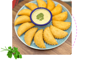A platter of corn empanadas with a garlic salsa