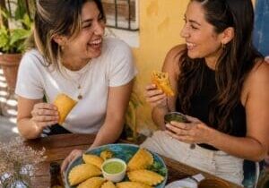 Two women enjoying golden empanadas with dipping sauces - Illustrative Image